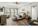 Bright main bedroom with a ceiling fan, large windows, wood flooring, a bed, and multiple pieces of furniture at 16310 Rock Coast Dr, Winter Garden, FL 34787