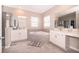 Bright bathroom featuring a soaking tub, dual sinks, vanity and large mirrors at 187 Aces High Ln, Davenport, FL 33896