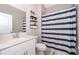 Bright bathroom with white vanity, toilet, and blue striped shower curtain at 187 Aces High Ln, Davenport, FL 33896