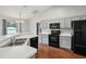 Well-lit kitchen featuring black appliances, light gray cabinets, and stylish wood-look flooring at 25 Maple Crse, Ocklawaha, FL 32179