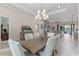 Open-concept dining area with a modern chandelier, neutral decor, and wood-look tile floors at 31746 Red Tail Blvd, Sorrento, FL 32776