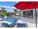 Beautiful backyard featuring a pool, spa, lounge area, and outdoor dining under a bright red umbrella at 31746 Red Tail Blvd, Sorrento, FL 32776