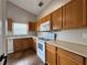 Well-lit kitchen with wood cabinetry, white appliances, tile flooring, and a bright window at 324 Anchovie Ct, Kissimmee, FL 34759
