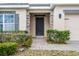 Close-up of front door, featuring stone accents, dark door, and manicured bushes at 9518 Lynwood St, Clermont, FL 34711