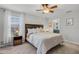 Serene main bedroom with a ceiling fan, soft carpet, a window with blinds, and a view into ensuite bathroom at 9518 Lynwood St, Clermont, FL 34711