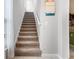 Carpeted staircase with white railing ascends to the upper level of the home, with a peek of the kitchen at 9518 Lynwood St, Clermont, FL 34711