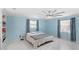 Bedroom with pastel blue walls, gray accents, and large windows with sheer curtains at 11595 Sw 134 Ct, Dunnellon, FL 34432