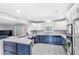 Bright eat-in kitchen featuring white cabinetry, blue lower cabinets, and an island with bar seating at 11595 Sw 134 Ct, Dunnellon, FL 34432