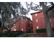 Exterior view of a red brick apartment building with lush greenery and mature trees surrounding it at 122 Vista Verdi Cir # 216, Lake Mary, FL 32746