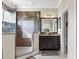 Bathroom featuring a tiled glass shower, dual sinks, dark wood cabinets, and granite countertops at 13221 Fountainbleau Dr, Clermont, FL 34711