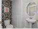 Chic powder room featuring patterned wallpaper and a pedestal sink with a round mirror at 14031 Centerline Dr, Orlando, FL 32827