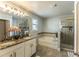 Well-lit bathroom featuring a double vanity, soaking tub, and glass-enclosed shower with tile accents at 14664 Spotted Sandpiper Blvd, Winter Garden, FL 34787