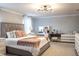Stylish bedroom featuring a tufted headboard, neutral color palette, and vanity with a decorative light fixture at 14664 Spotted Sandpiper Blvd, Winter Garden, FL 34787