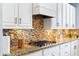 Close up of kitchen showcasing modern appliances, granite counters, mosaic tile backsplash, and white cabinets at 14664 Spotted Sandpiper Blvd, Winter Garden, FL 34787