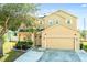 Charming two-story home with manicured landscaping, tan paint, and solar panels on the roof at 1602 Pine Ridge Dr, Davenport, FL 33896