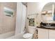 Bathroom featuring a tiled shower-tub, granite countertop and vanity with a round mirror at 195 Maple Dr, Kissimmee, FL 34759