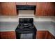 Close-up of the electric range in the kitchen with wood cabinets and neutral walls at 206 E South St # 4031, Orlando, FL 32801