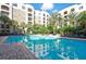 Sparkling blue pool with surrounding lounge chairs, palm trees, and condo complex in background at 206 E South St # 4031, Orlando, FL 32801