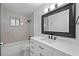 Bright bathroom with a large framed mirror and a white vanity with black hardware at 211 S Deerwood Ave, Orlando, FL 32825