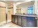 Bathroom featuring a granite countertop, dual sinks, a walk-in shower, and modern fixtures at 2182 Cooper Bell Pl, Kissimmee, FL 34747