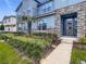 Charming townhome entrance featuring stone accents, a modern front door, and beautiful landscaping at 2182 Cooper Bell Pl, Kissimmee, FL 34747