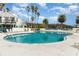 Large outdoor community pool surrounded by lounge chairs and palm trees under a sunny blue sky at 2552 Woodgate Blvd # 204, Orlando, FL 32822