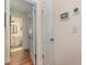 Hallway view towards a bathroom, showing wood floors and thermostat at 2552 Woodgate Blvd # 204, Orlando, FL 32822