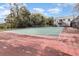 Well-maintained community tennis court with a net surrounded by mature trees, providing shade at 2552 Woodgate Blvd # 204, Orlando, FL 32822