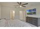 Bright bedroom features a ceiling fan, gray dresser and a large-screen TV with a nature scene at 5663 Keaton Springs Dr, Lakeland, FL 33811