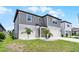 View of a two-story home with gray siding, a white garage door, manicured lawn, and decorative rock and shrub accents at 5663 Keaton Springs Dr, Lakeland, FL 33811