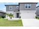 Two-story home featuring a gray exterior, a two-car garage, and a well-maintained front yard with decorative landscaping at 5663 Keaton Springs Dr, Lakeland, FL 33811