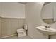 Clean half bathroom with pedestal sink, and toilet with wainscotting at 5663 Keaton Springs Dr, Lakeland, FL 33811