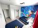 A playful bedroom featuring twin beds and a vibrant mural of Mickey Mouse characters at 695 Whistling Straits Blvd, Davenport, FL 33896