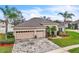 Exterior elevation showing a home with a 3-car garage, landscaped yard, and brick driveway at 719 Postrio Way, Ocoee, FL 34761