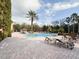 Community swimming pool with lounge chairs, palm trees, and sunny skies at 8010 Tuscany Way # 5206, Davenport, FL 33896