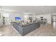 Wide angle view of open-concept living room and kitchen area with gray sectional sofa and TV at 8903 Caroline Bay Ct, Kissimmee, FL 34747