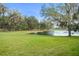 Scenic view of a sprawling green backyard with a tranquil pond surrounded by trees and lush greenery at 10361 Mallard Landings Way, Orlando, FL 32832