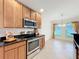 Kitchen with stainless steel appliances, wood cabinets, and granite countertops, leading into breakfast nook at 10840 Cabbage Tree Loop, Orlando, FL 32825