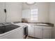 A well-lit laundry room is equipped with white cabinets, a sink, and modern washer and dryer units at 11237 Camden Park Dr, Windermere, FL 34786