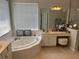 Main bathroom featuring a jacuzzi tub, vanity with sink, and large mirror at 11474 Claymont Cir, Windermere, FL 34786