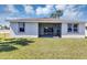 Home's rear exterior with a screened lanai, surrounded by a lush green lawn at 1306 Windward Oaks Loop, Auburndale, FL 33823