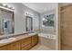 Bathroom featuring double vanity, soaking tub, glass shower, and window offering natural light at 1306 Windward Oaks Loop, Auburndale, FL 33823