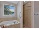 Bright bathroom featuring a soaking tub, separate tiled shower, and window at 1306 Windward Oaks Loop, Auburndale, FL 33823