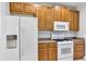 Close-up of kitchen showcasing wooden cabinets, granite countertops, and white appliances at 1306 Windward Oaks Loop, Auburndale, FL 33823