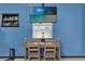 Cozy dining area with a wooden table set, a flat-screen TV, and charming decor against a vibrant blue wall at 1417 Independence Ave, Deltona, FL 32725