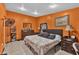 Main bedroom boasts orange walls, dresser, TV, and large bed with patterned bedding at 1417 Independence Ave, Deltona, FL 32725