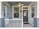 Close up of attractive front porch with ceiling fan and white railings and nicely landscaped yard at 14472 Chinese Elm Dr, Orlando, FL 32828