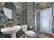 Stylish powder room showcasing patterned wallpaper, pedestal sink, and walk-in shower at 15143 Ovation Dr, Winter Garden, FL 34787