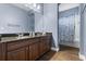 Bathroom boasts dual sink granite vanity and tiled shower with patterned curtain at 15143 Ovation Dr, Winter Garden, FL 34787