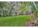 Lush backyard featuring manicured lawn, mature trees, and access to a screened-in pool area at 210 Torcaso Ct, Winter Springs, FL 32708